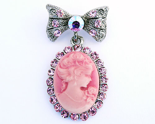 Se mere om broche i sølvfarve med ovalt motiv af lyserød dame i web-butikken
